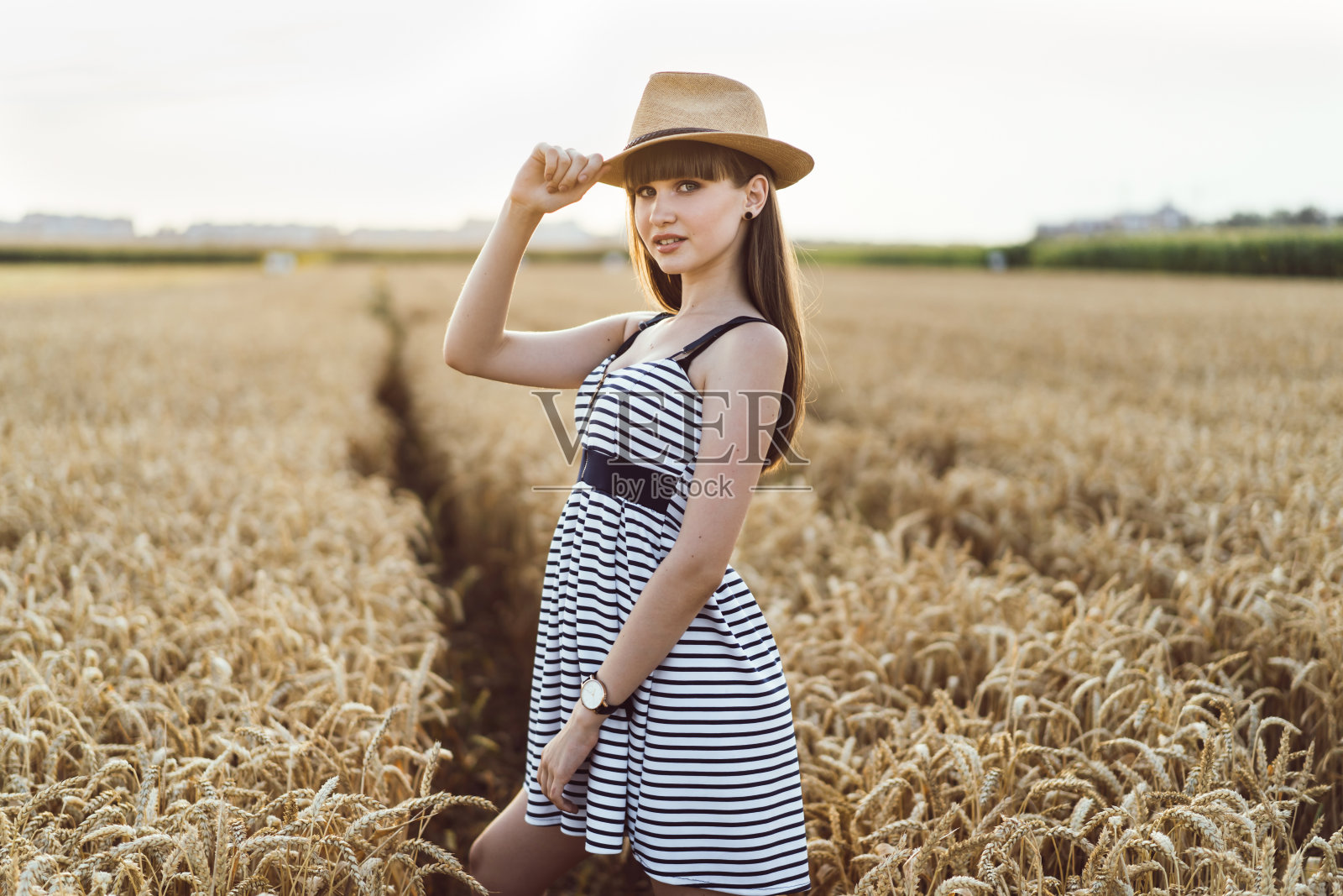 漂亮的黑发女孩穿着浅色衣服在麦田里散步照片摄影图片