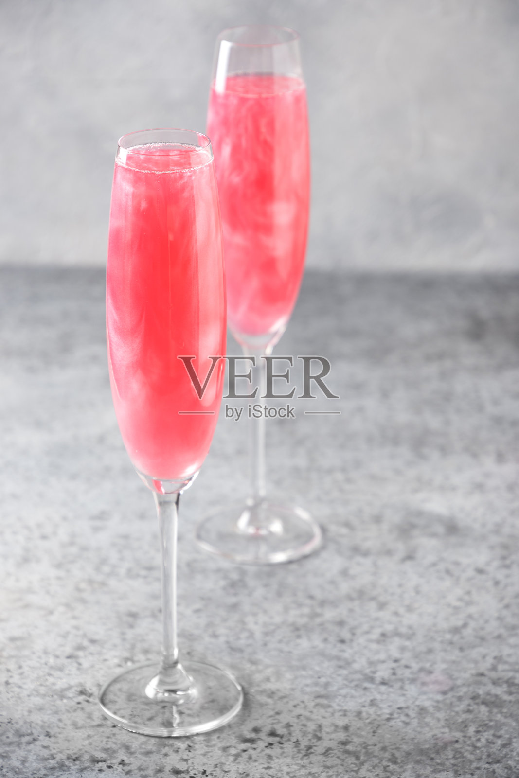 两杯起泡的玫瑰葡萄酒与闪烁的迷迭香装饰在灰色。垂直格式。照片摄影图片