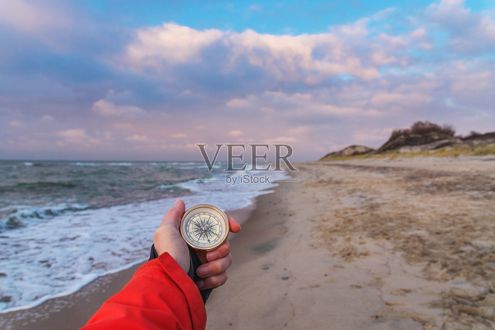 第一人称视角的女性手与指南针在一个美丽的海洋景观的背景。导航的概念，寻找自己的路径和方向的基本点照片摄影图片