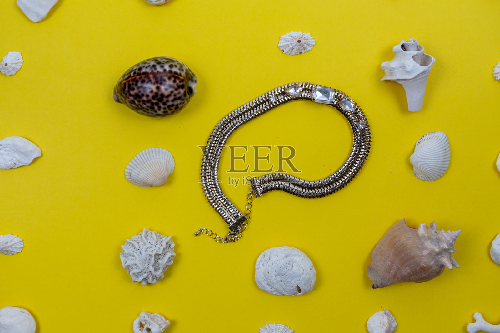 黄色背景上的人造珠宝和贝壳照片摄影图片