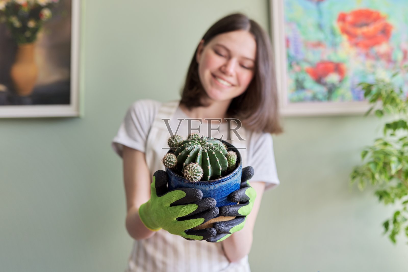 十几岁的女孩在花盆里抱着仙人掌。爱好和休闲，家庭园艺，室内植物照片摄影图片