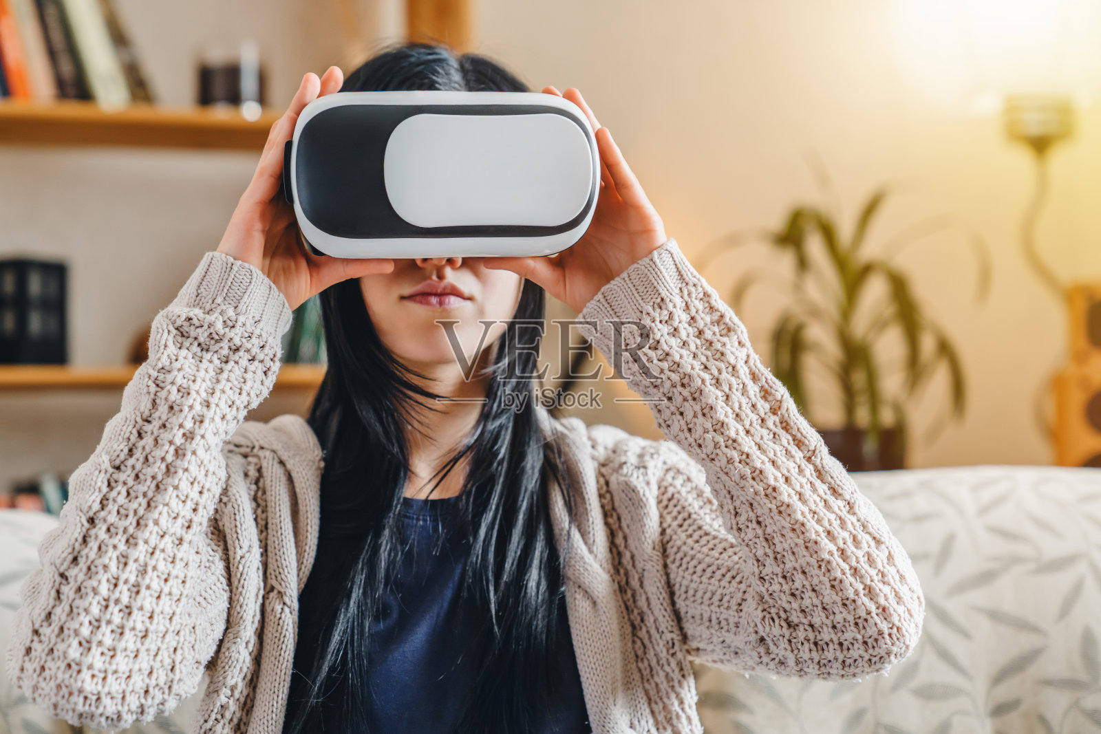 年轻女子戴着VR头戴坐在沙发上照片摄影图片