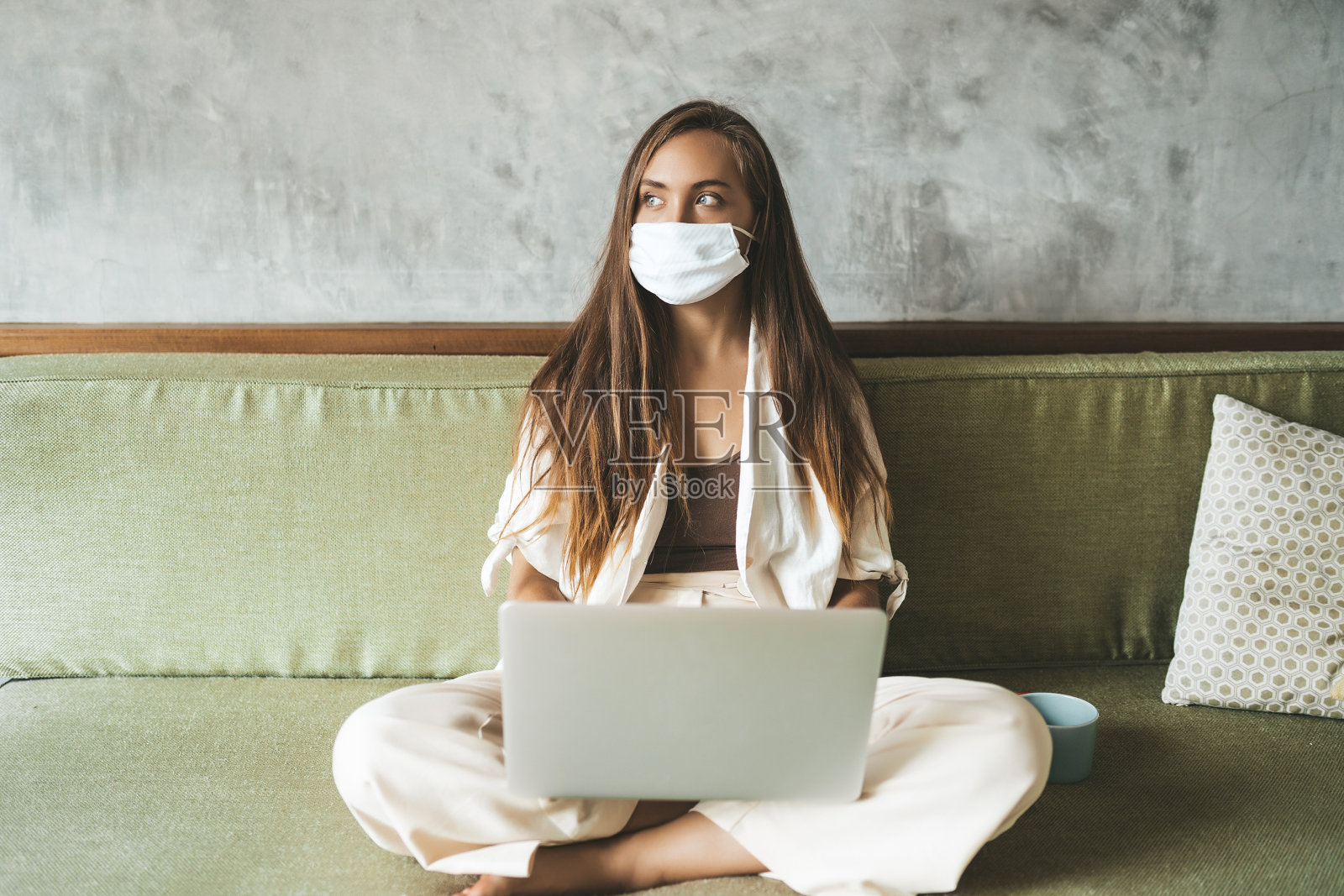 妇女在自我隔离和隔离期间，佩戴医用防护口罩在家使用电脑工作。本空间照片摄影图片