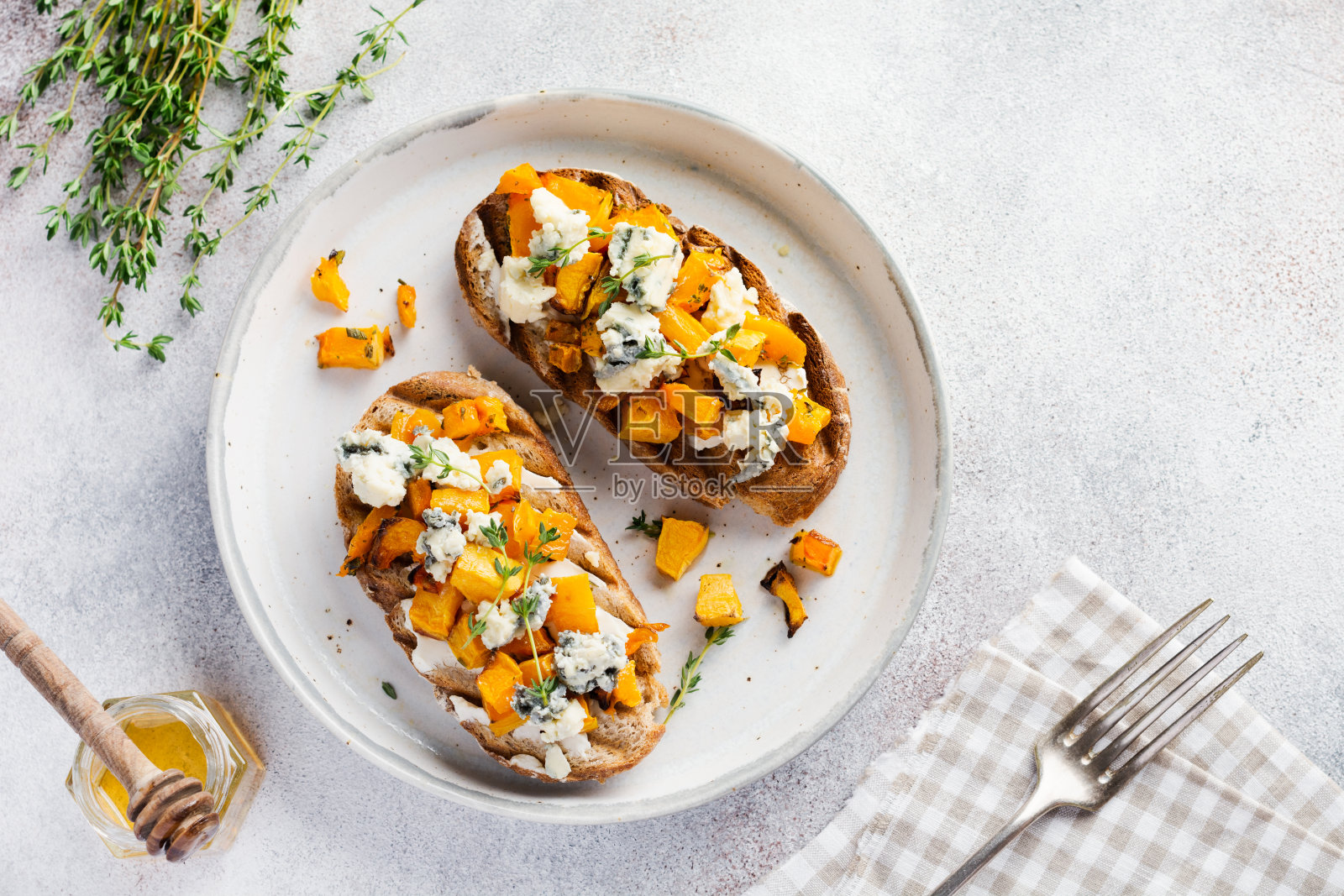 烤南瓜三明治与dorblu奶酪与蓝色霉菌，蜂蜜和百里香在混凝土的旧灯光背景。前视图。照片摄影图片