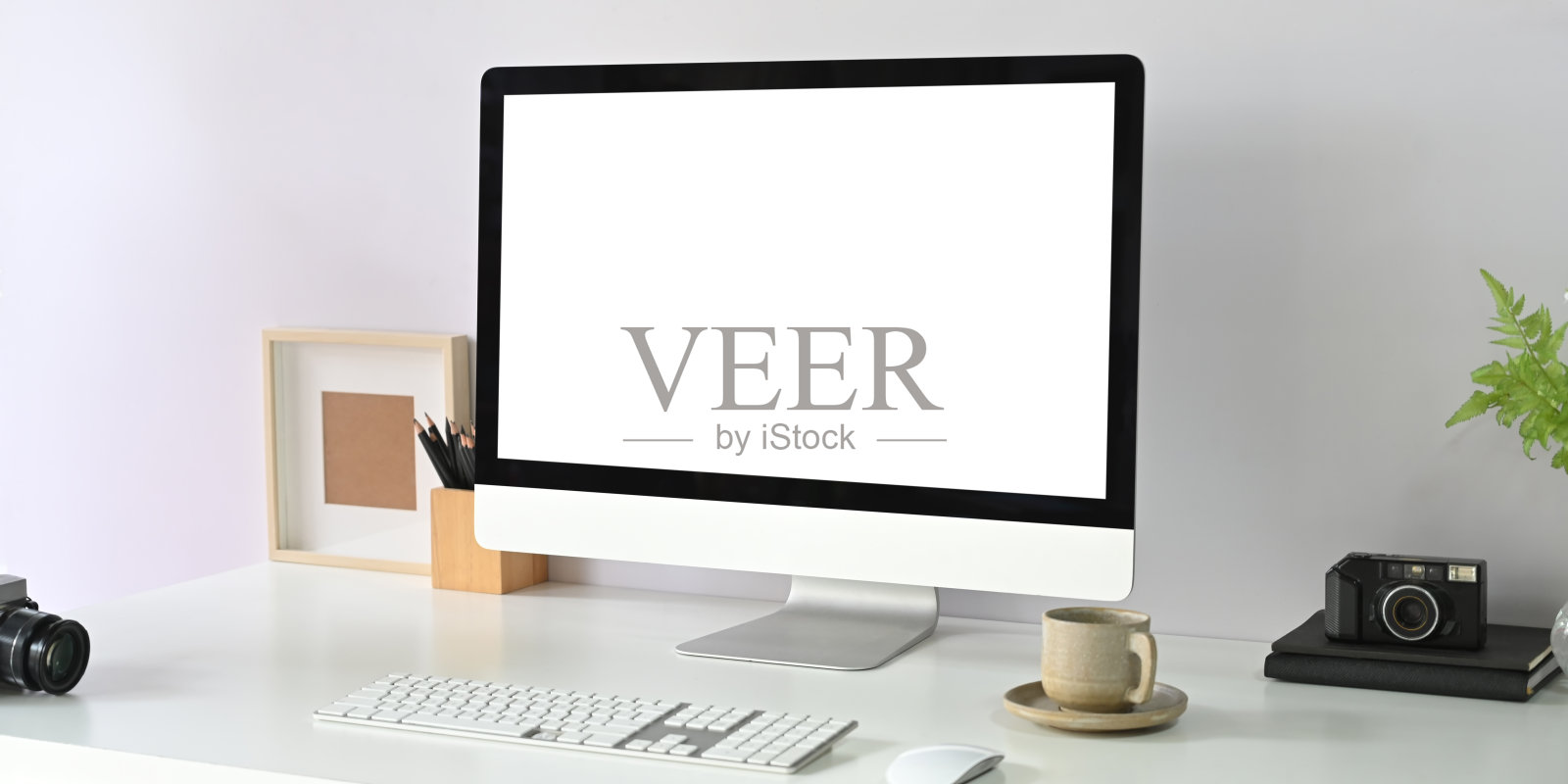 一个空白屏幕的电脑显示器放在一张白色的办公桌上，周围是办公设备。照片摄影图片