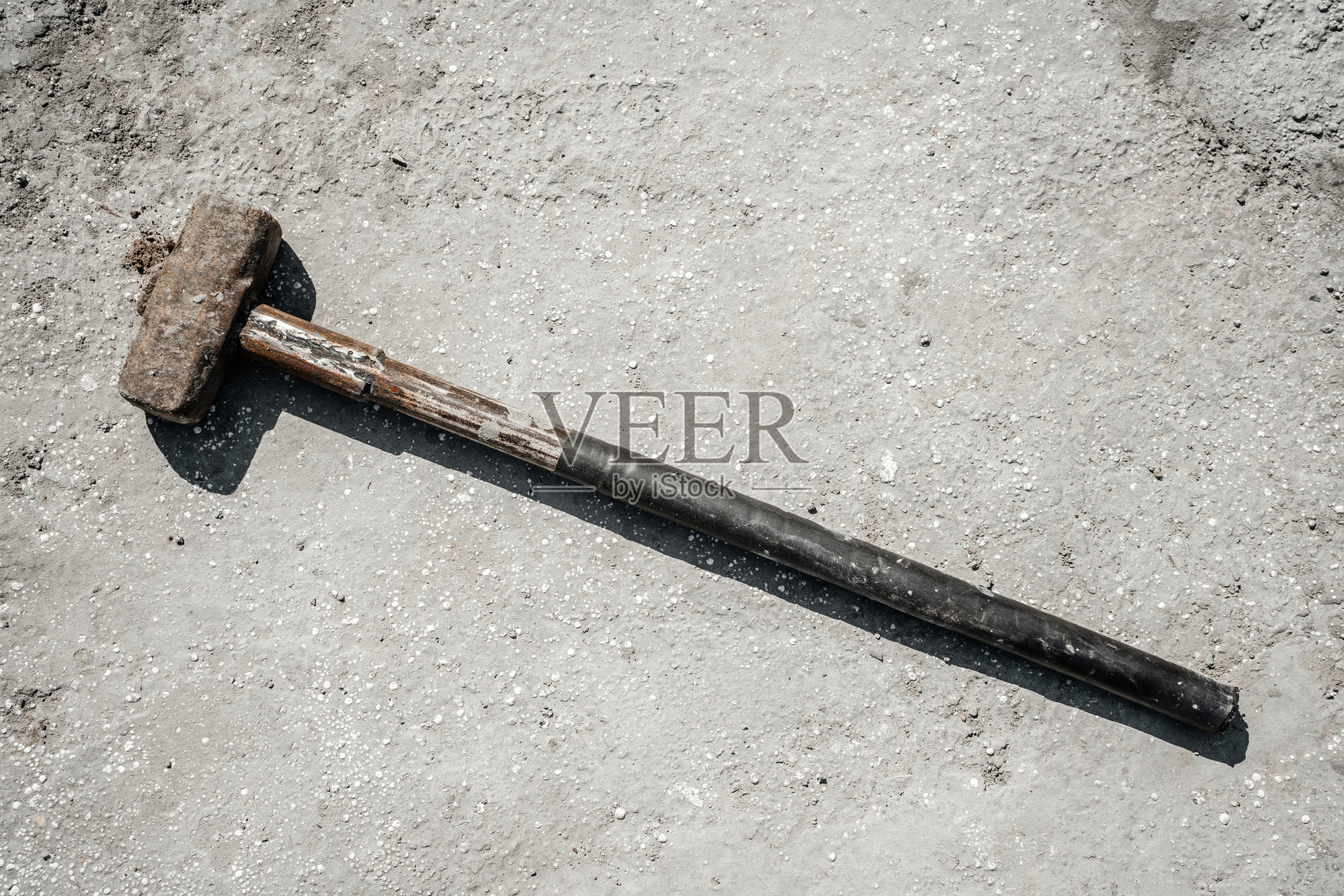 混凝土板和混凝土石头上生锈的大锤。照片摄影图片