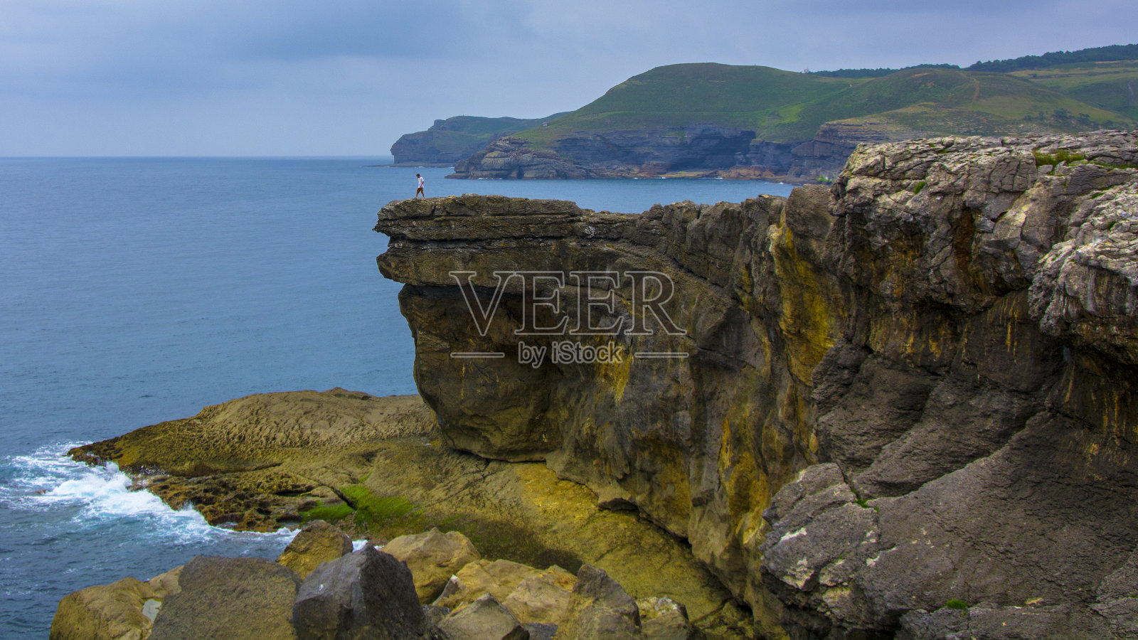 坎塔布里安悬崖，一个人在悬崖边上若隐若现。照片摄影图片