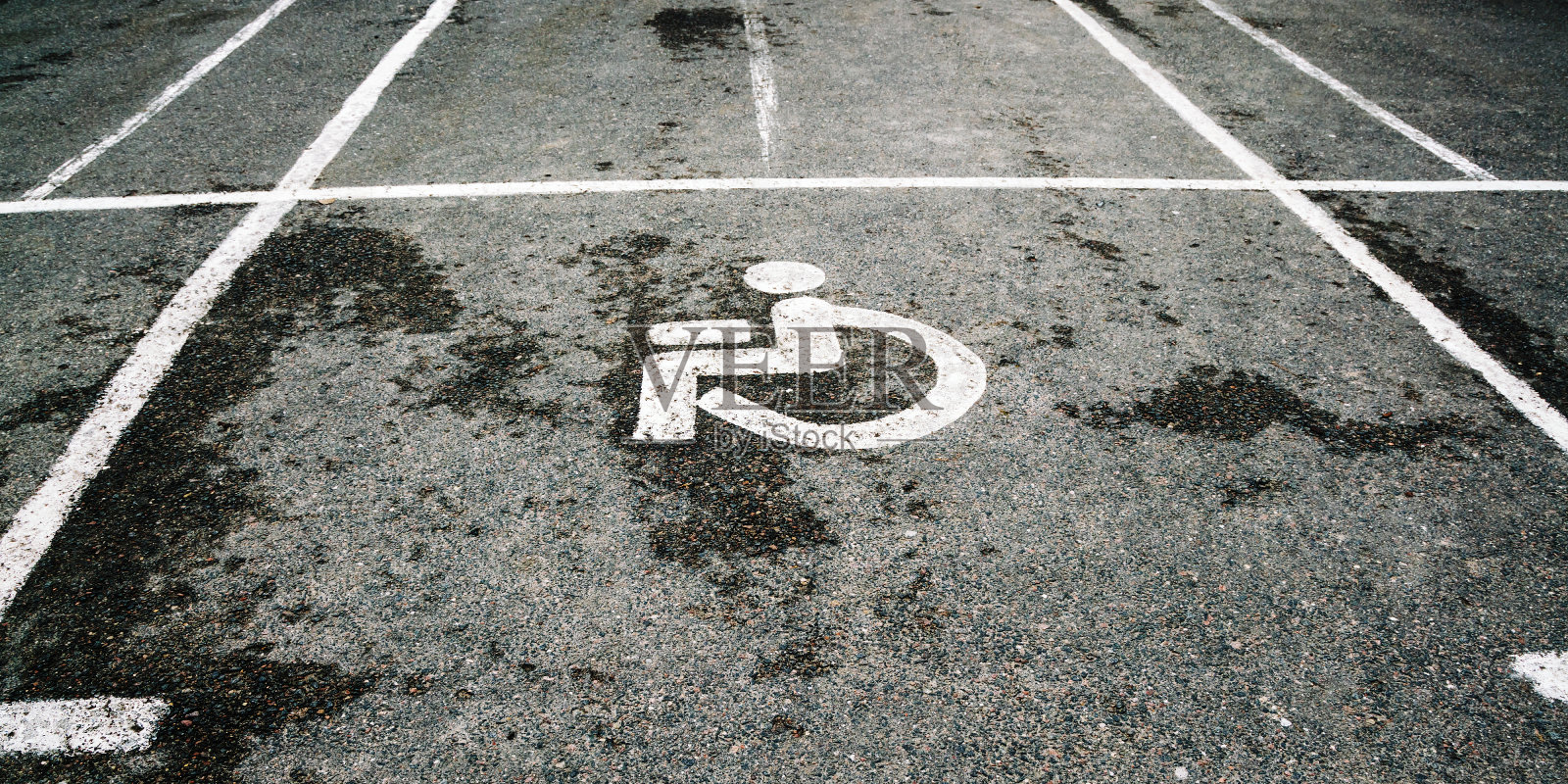 用白线和灰色湿沥青上的特殊标志分隔的残疾停车场照片摄影图片