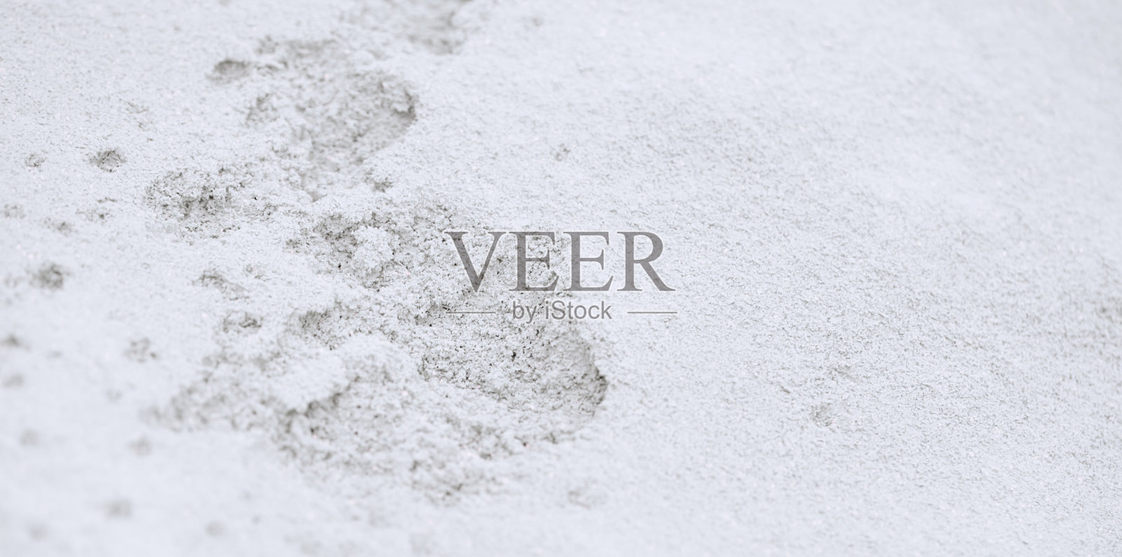 雪地背景下的一步。脚印在白色的雪地背景。照片摄影图片