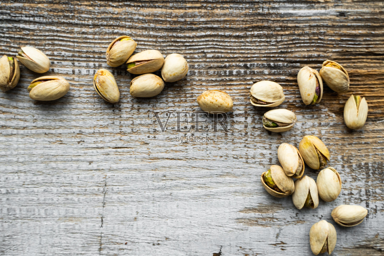 古色古香的木头桌子上散落着开心果。开心果是一种健康的素食蛋白质营养食品。开心果放在乡下的老木头上。照片摄影图片