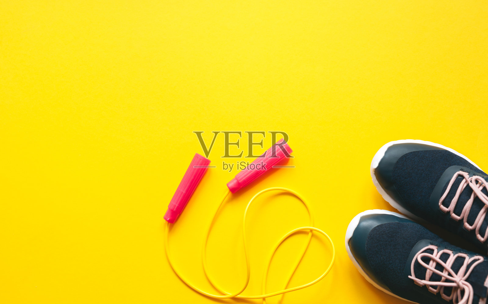 跳绳和黄色背景的运动鞋。极简主义的健康概念。俯视图和复制空间平铺。照片摄影图片