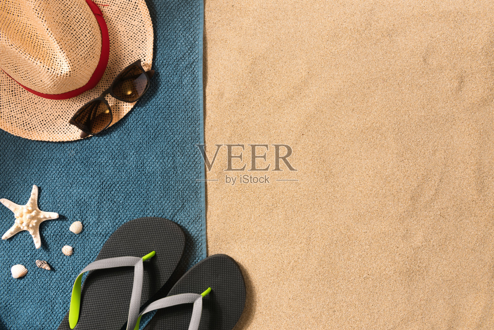 暑假的作文。人字拖，帽子和太阳镜上的沙子背景。旅游度假的概念。夏天的背景。由毛巾制成的边饰照片摄影图片