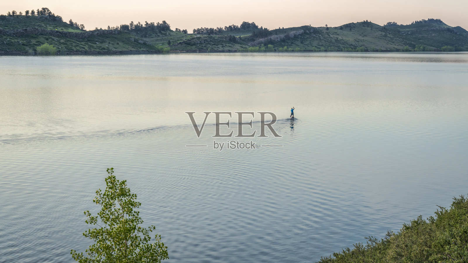 夏日的黎明，山间的湖上有一个孤独的划船者照片摄影图片