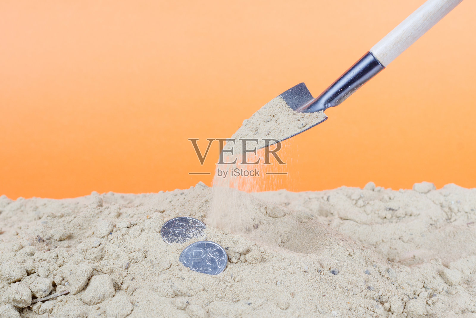 沙子里的两个金属卢布是用铲子埋在沙子里的照片摄影图片