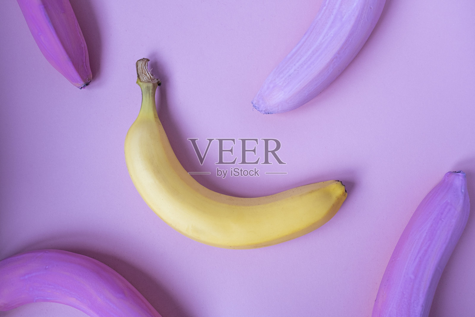 一个黄色的香蕉在粉红色背景的粉红色香蕉中。51、不如一切，概念独特。近距离创意食物模式在最小的风格。平躺，俯视图。照片摄影图片