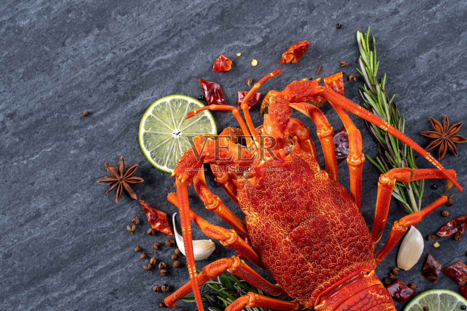 煮熟的龙虾，美味的晚餐海鲜套餐，刀叉在黑色石板背景，餐厅菜单设计。照片摄影图片