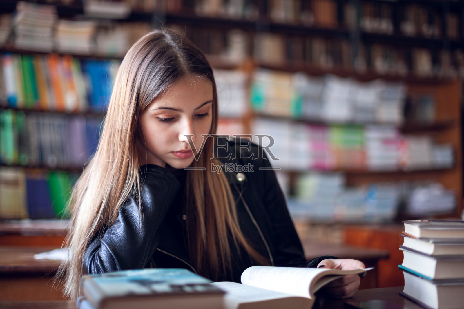 美丽的少女坐在图书馆里看书照片摄影图片