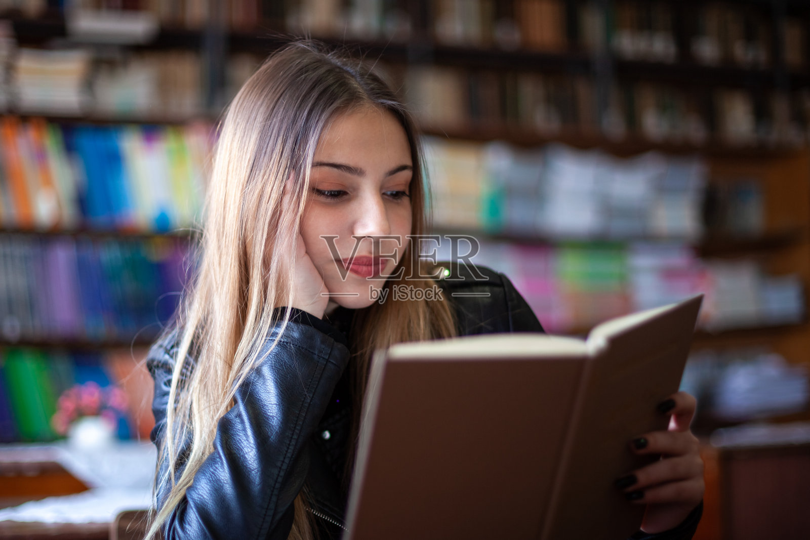 美丽的少女坐在图书馆里看书照片摄影图片