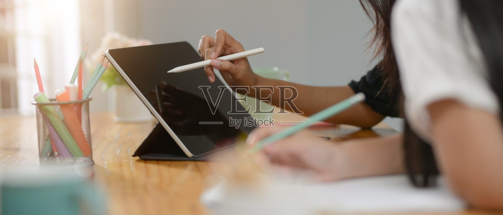 两个大学生在木桌上用数码板和文具一起做作业照片摄影图片