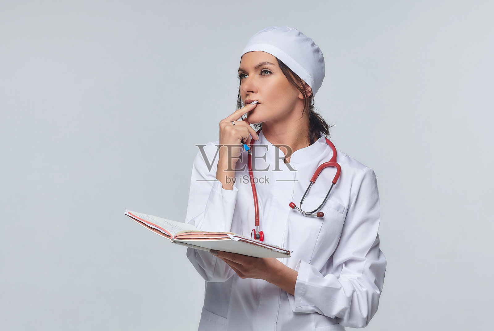 医学概念是女医生穿着白大褂，带着听诊器，医生。一名女医院工作人员看着摄像机微笑着说:工作室，白色背景照片摄影图片