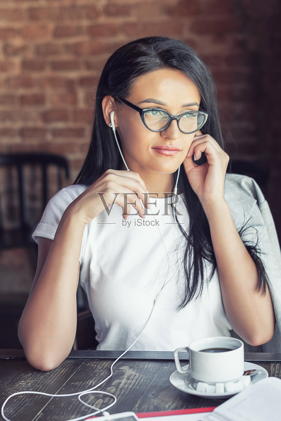 戴眼镜的女人在听音乐。照片摄影图片