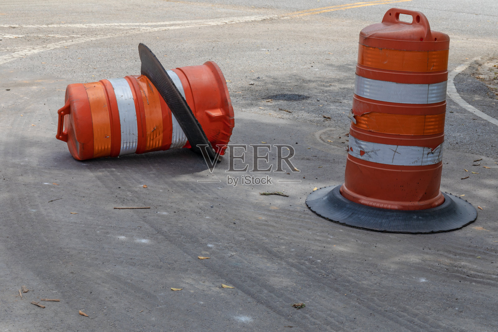 两个橙色和白色的交通安全桶，一个打翻了，比喻驾驶安全、危险和事故照片摄影图片