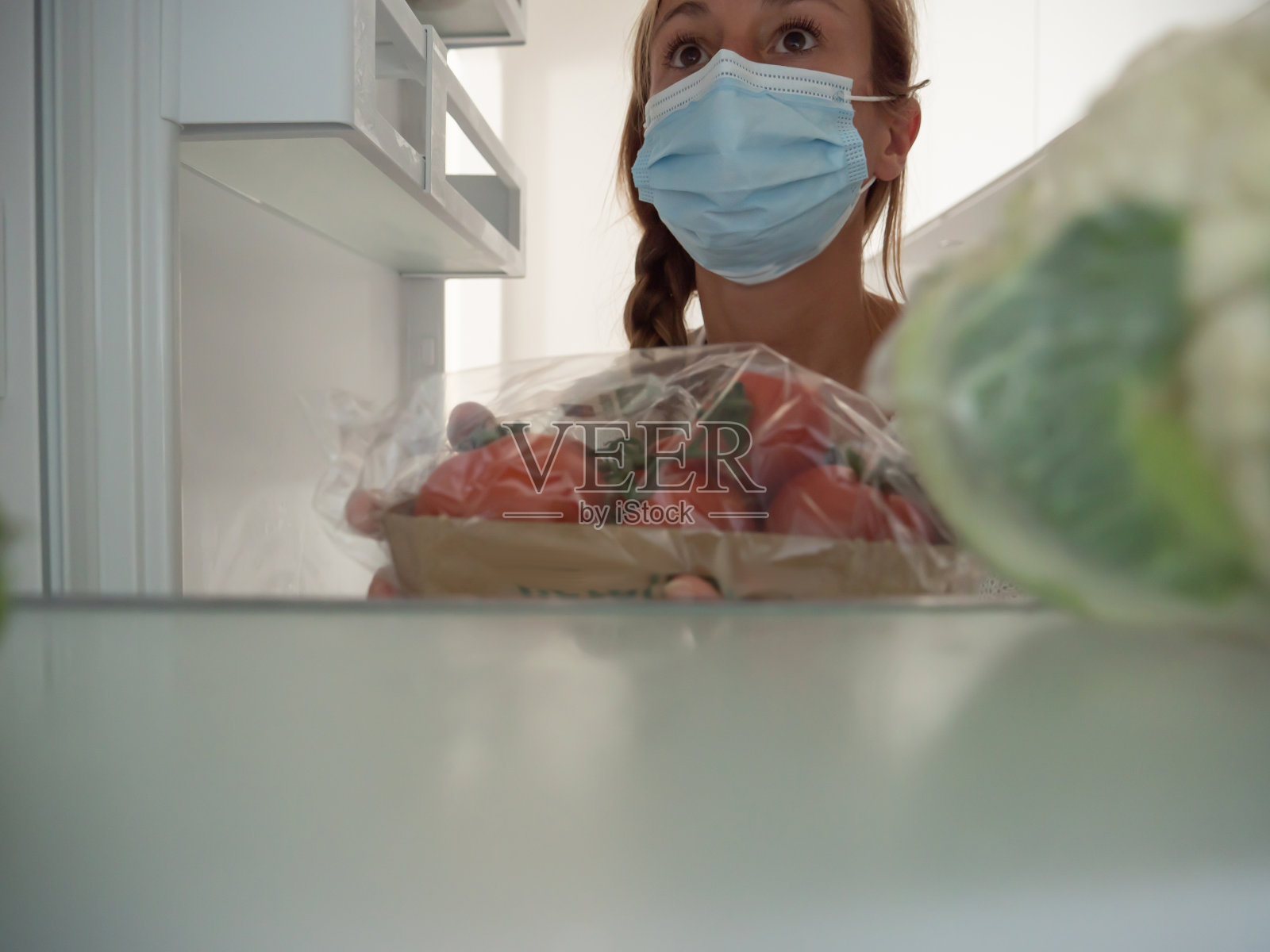 一名年轻女子将食品杂货放进冰箱照片摄影图片