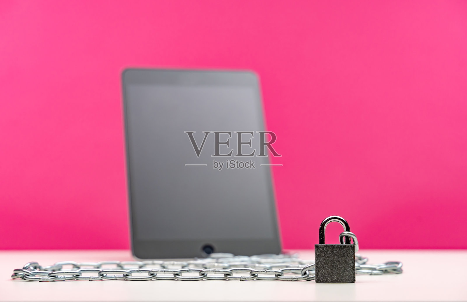 数字平板电脑锁定与挂锁和链在粉红色的背景照片摄影图片