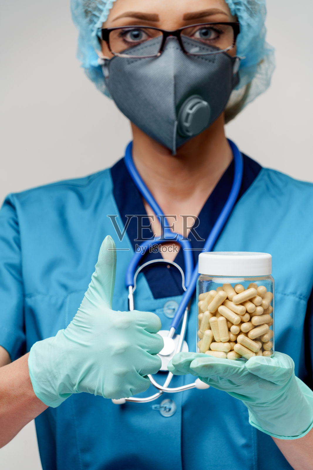 医生护士妇女戴着防护面具和橡胶或乳胶手套-持有药丸照片摄影图片