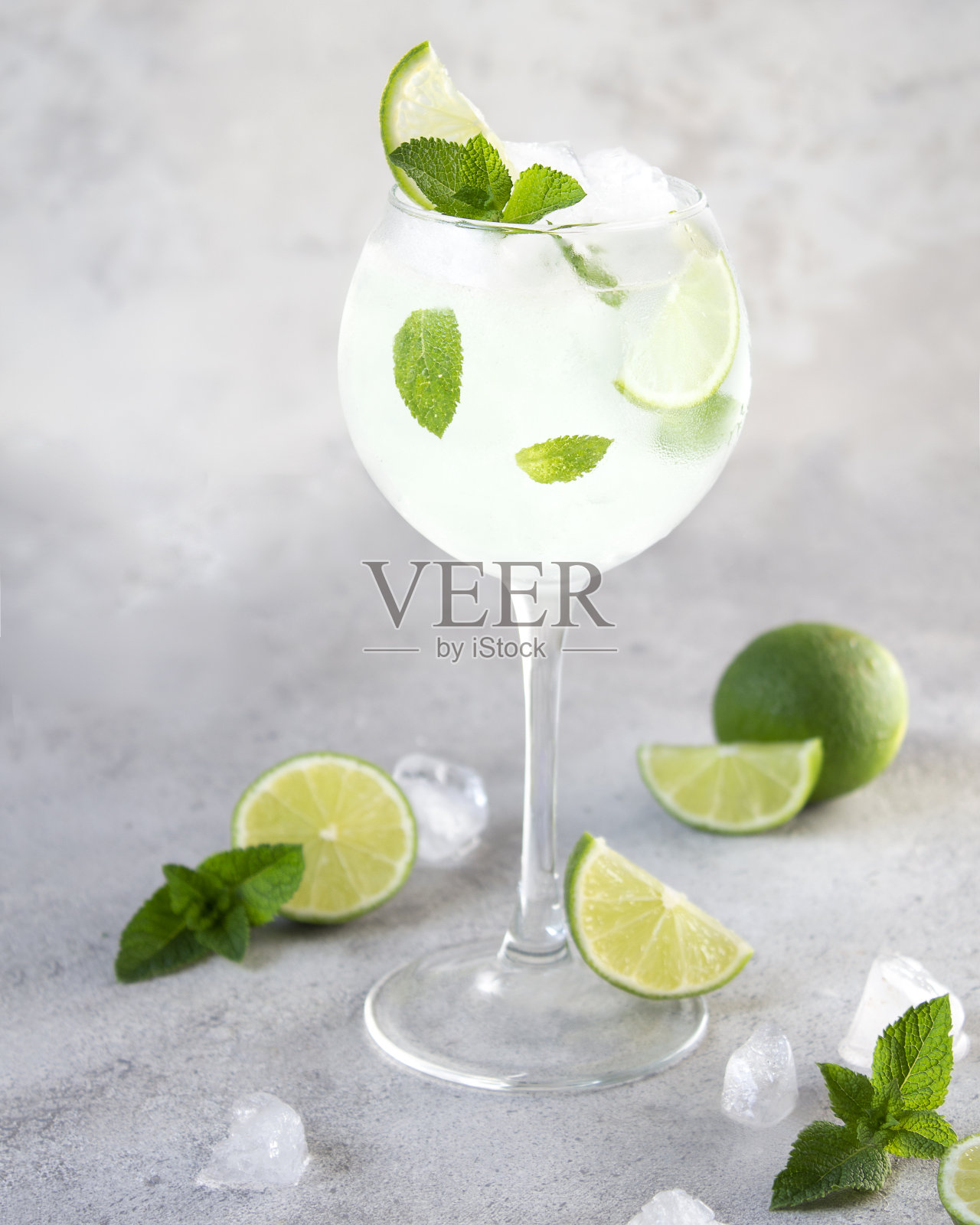 清新的柠檬水，柠檬和薄荷片放在玻璃杯里，在灰色的背景上蒸玻璃杯。目录的莫吉托广告。半个酸橙，加冰。夏季饮料的食物造型。本空间照片摄影图片