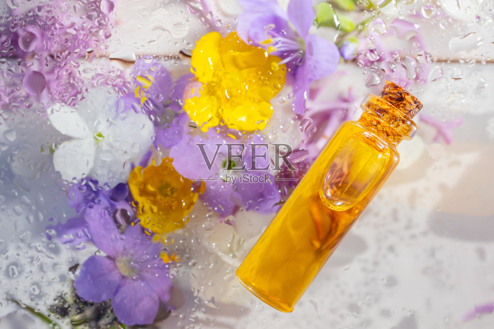 在绿色植物和鲜花的背景下，在玻璃小罐子里的天然化妆品精油。照片摄影图片