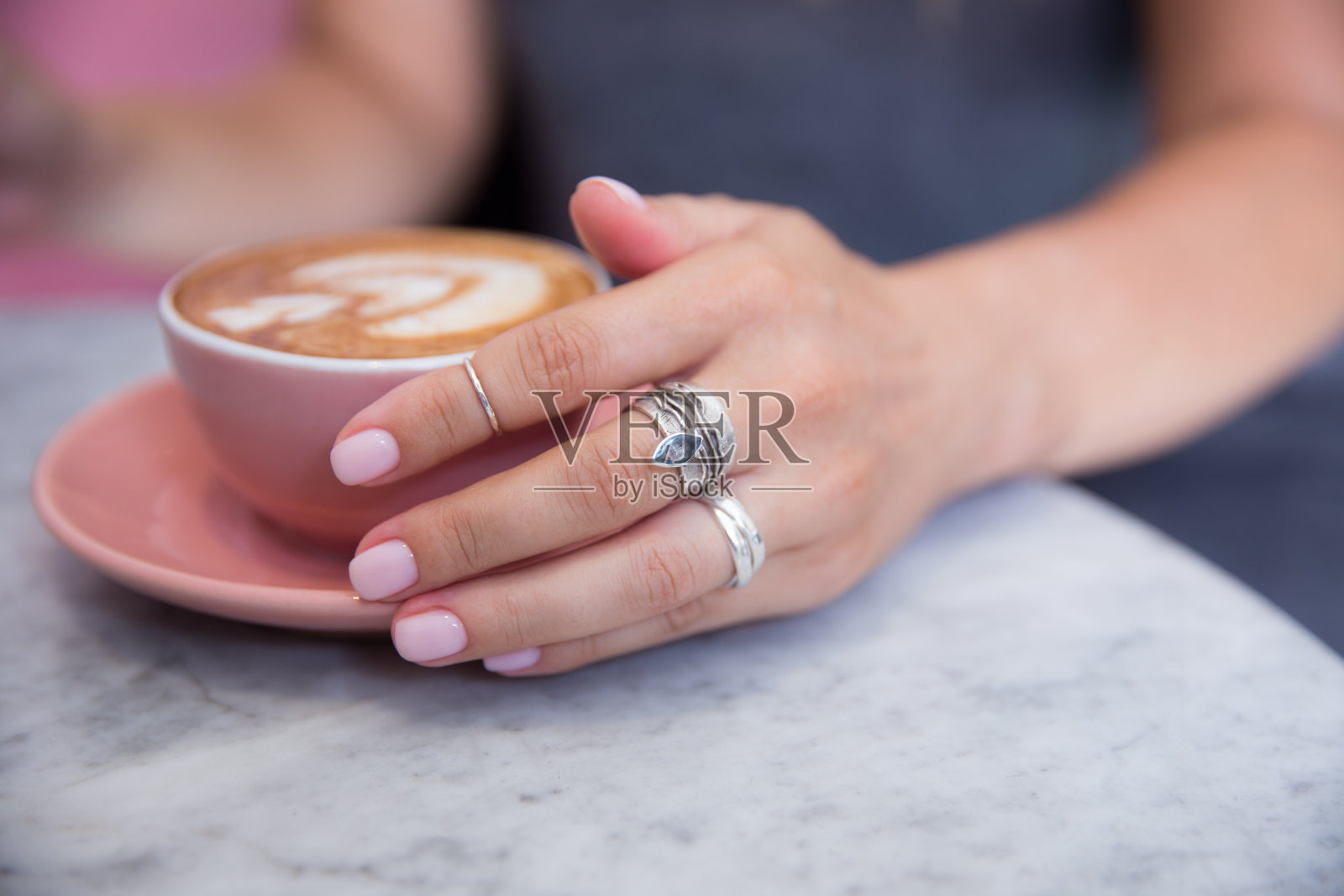 粉红色时髦的卡布奇诺杯握着美丽的女人的手照片摄影图片