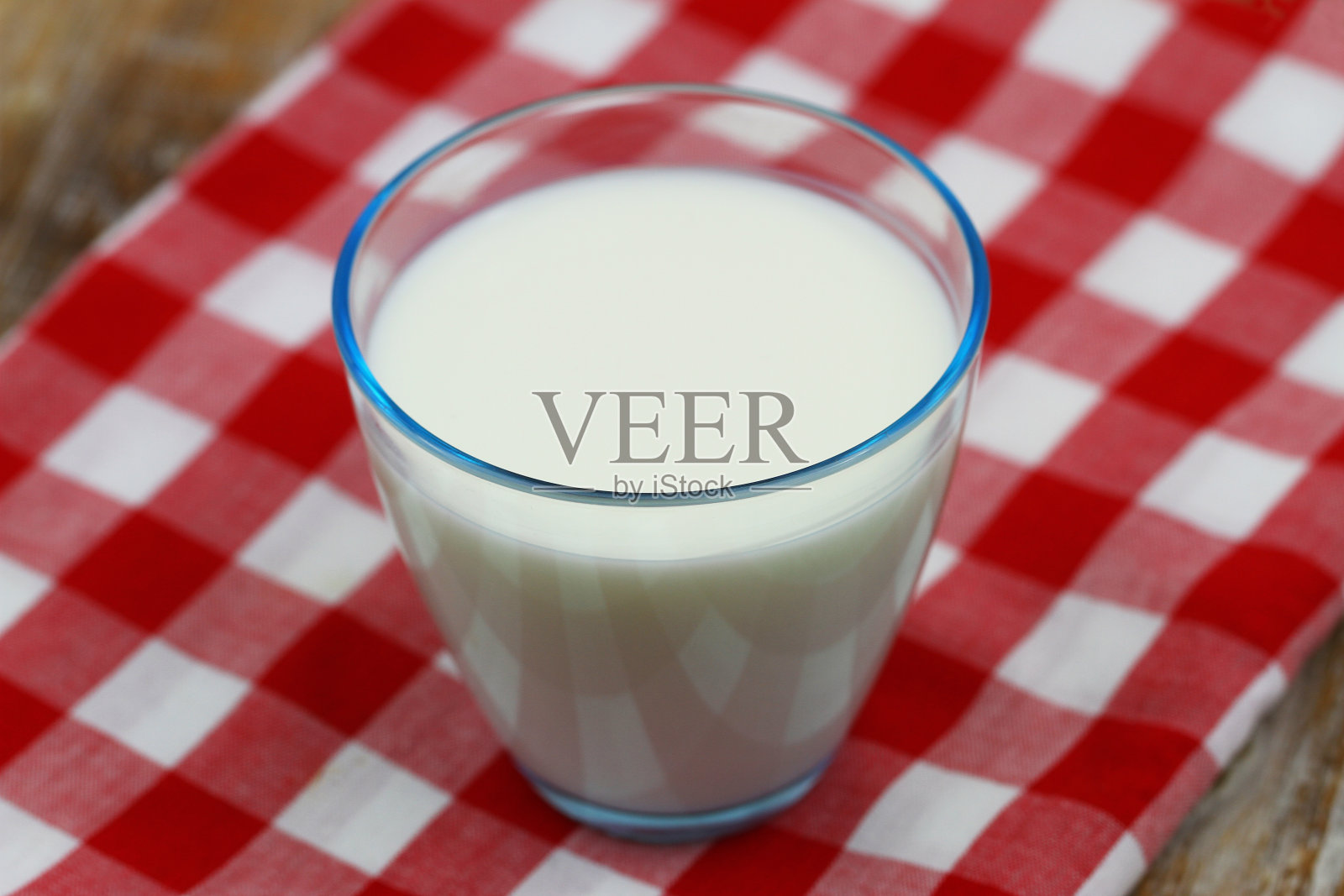 一杯牛奶放在红白格子布上照片摄影图片