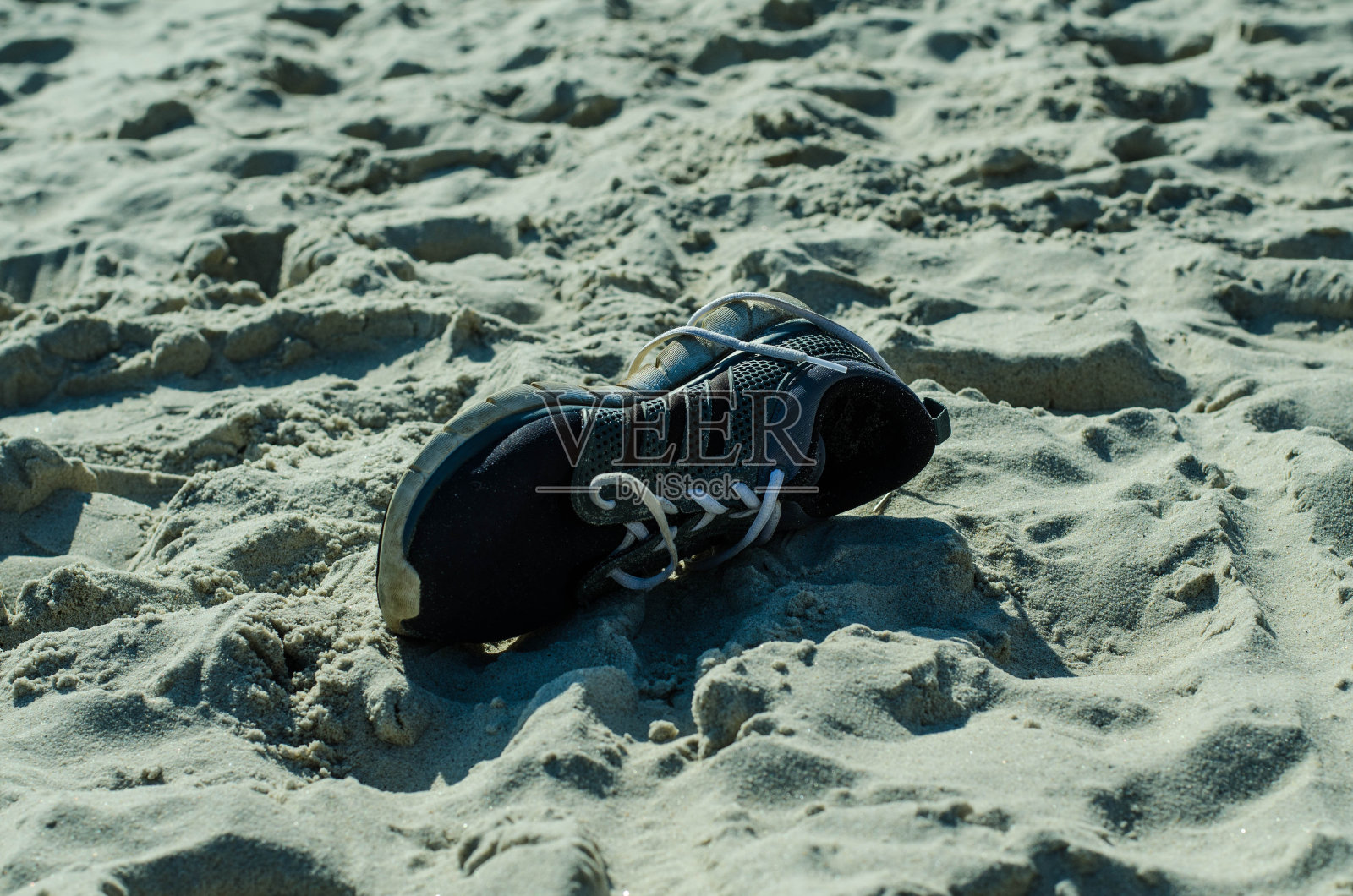 运动鞋。鞋类。失去的东西。海滩上的垃圾。照片摄影图片