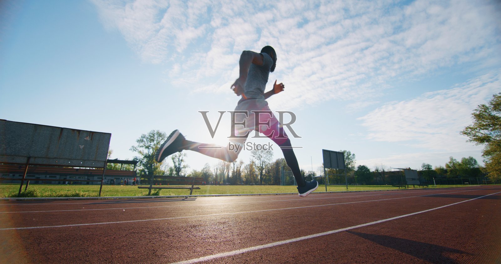 年轻的非洲男运动员在田径场上的跑道上跳跃的肖像。照片摄影图片