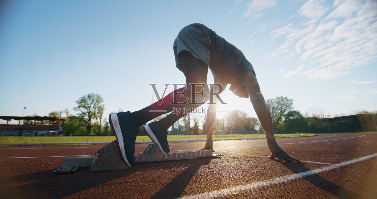 年轻的非洲男运动员在田径场上准备跳跃的肖像。照片摄影图片