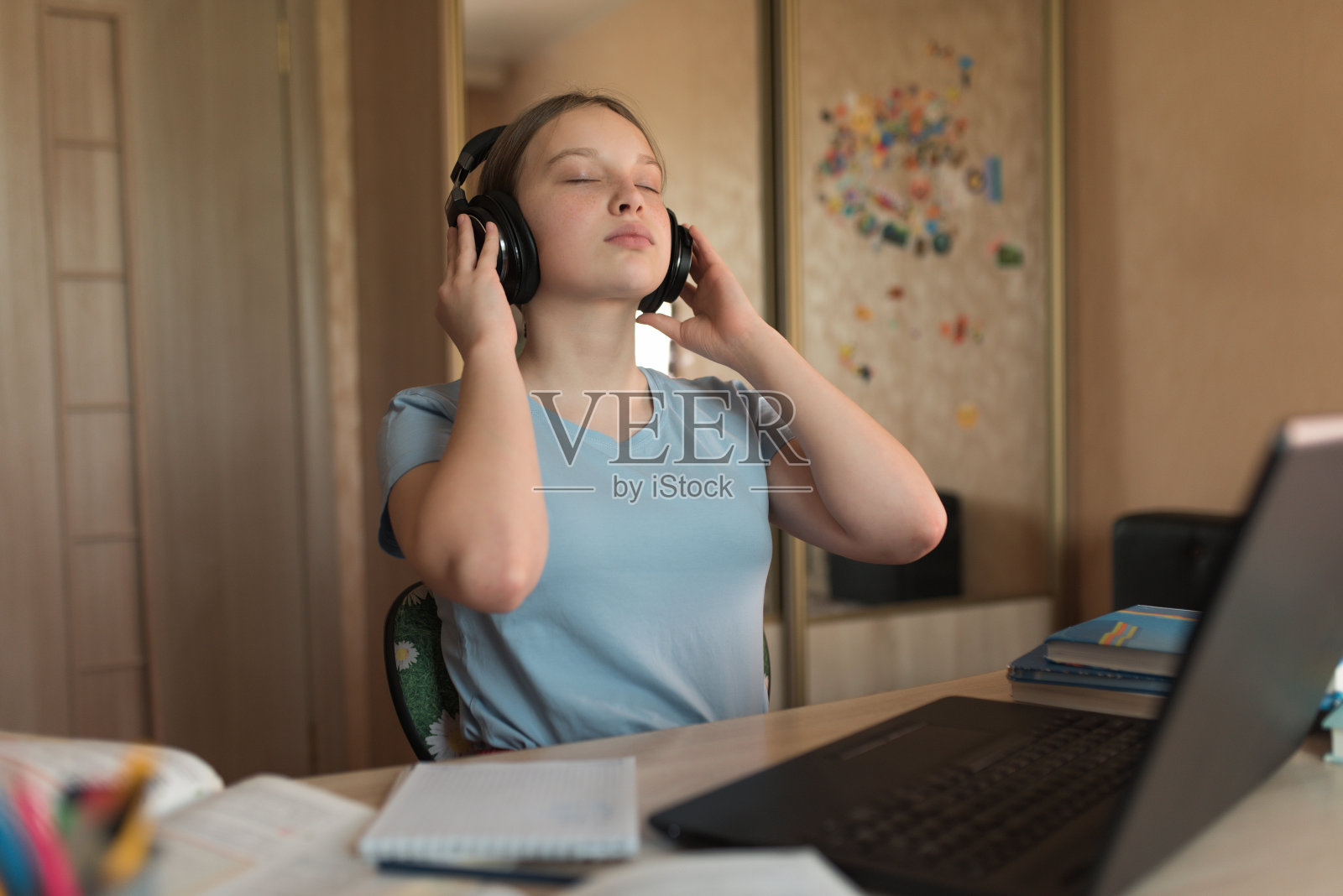 少女戴着耳机听音乐，在家里用笔记本电脑进行在线教育，心情愉悦和放松，在学校和学院休息和休息。照片摄影图片