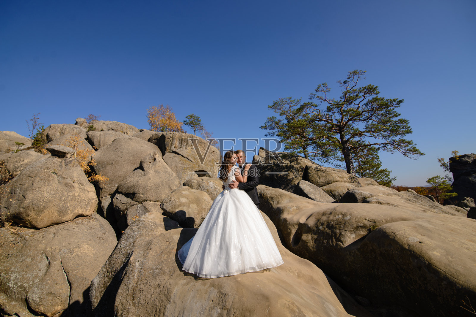 新娘和新郎在悬崖顶上拥抱。照片摄影图片
