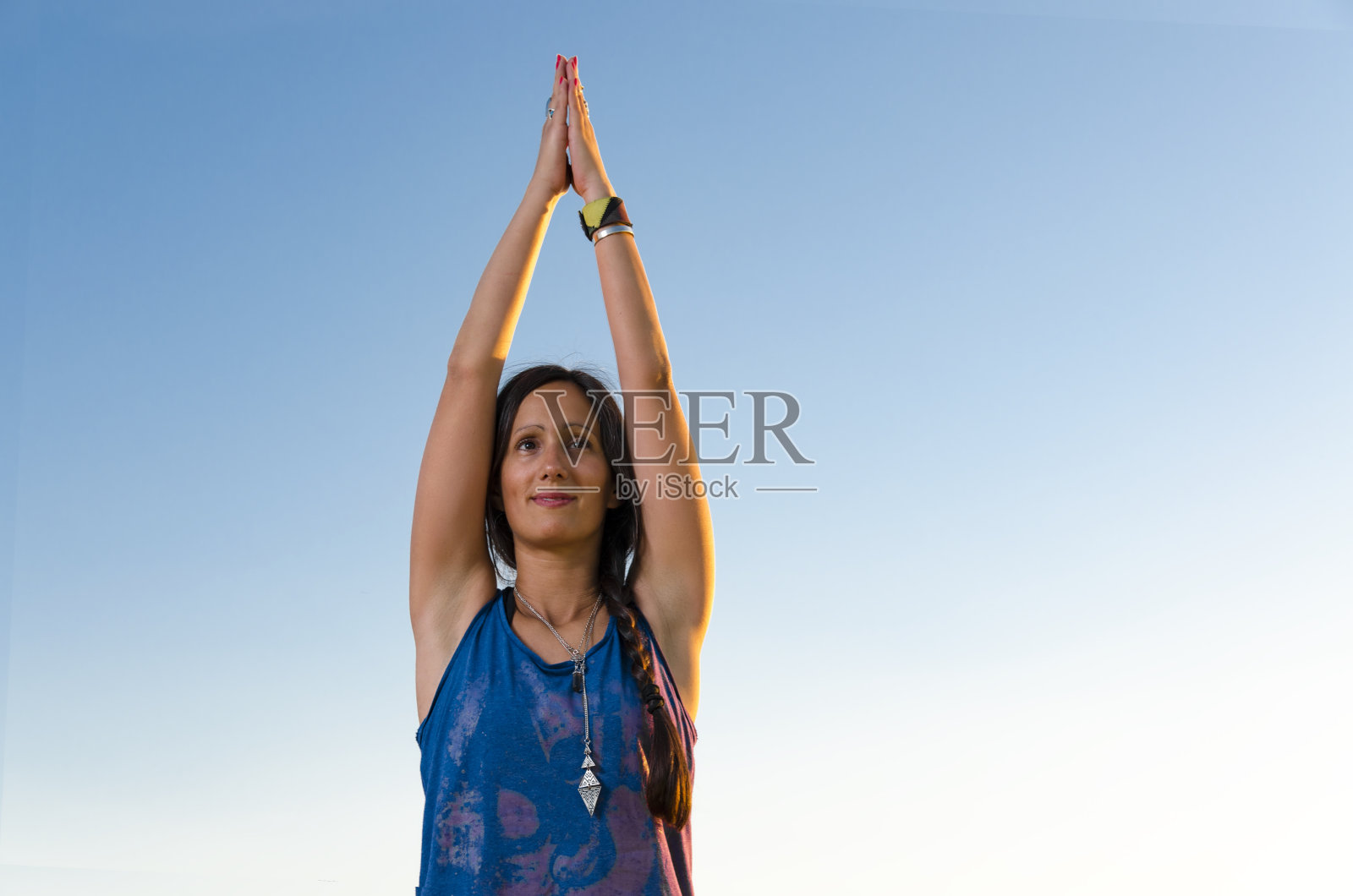 年轻美丽的女人特写镜头，瑜伽姿势在晴朗的蓝天照片摄影图片