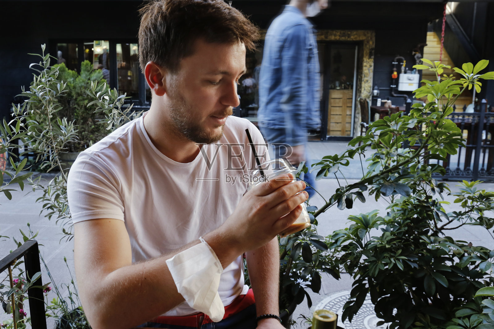 手持一杯冰拿铁和医疗口罩的男人照片摄影图片