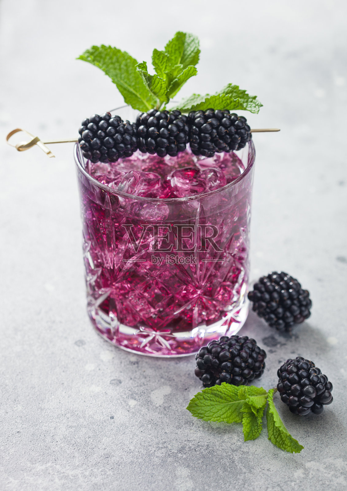 一杯清爽的夏日鸡尾酒，以黑莓，冰和薄荷为背景。苏打和酒精的混合物。照片摄影图片