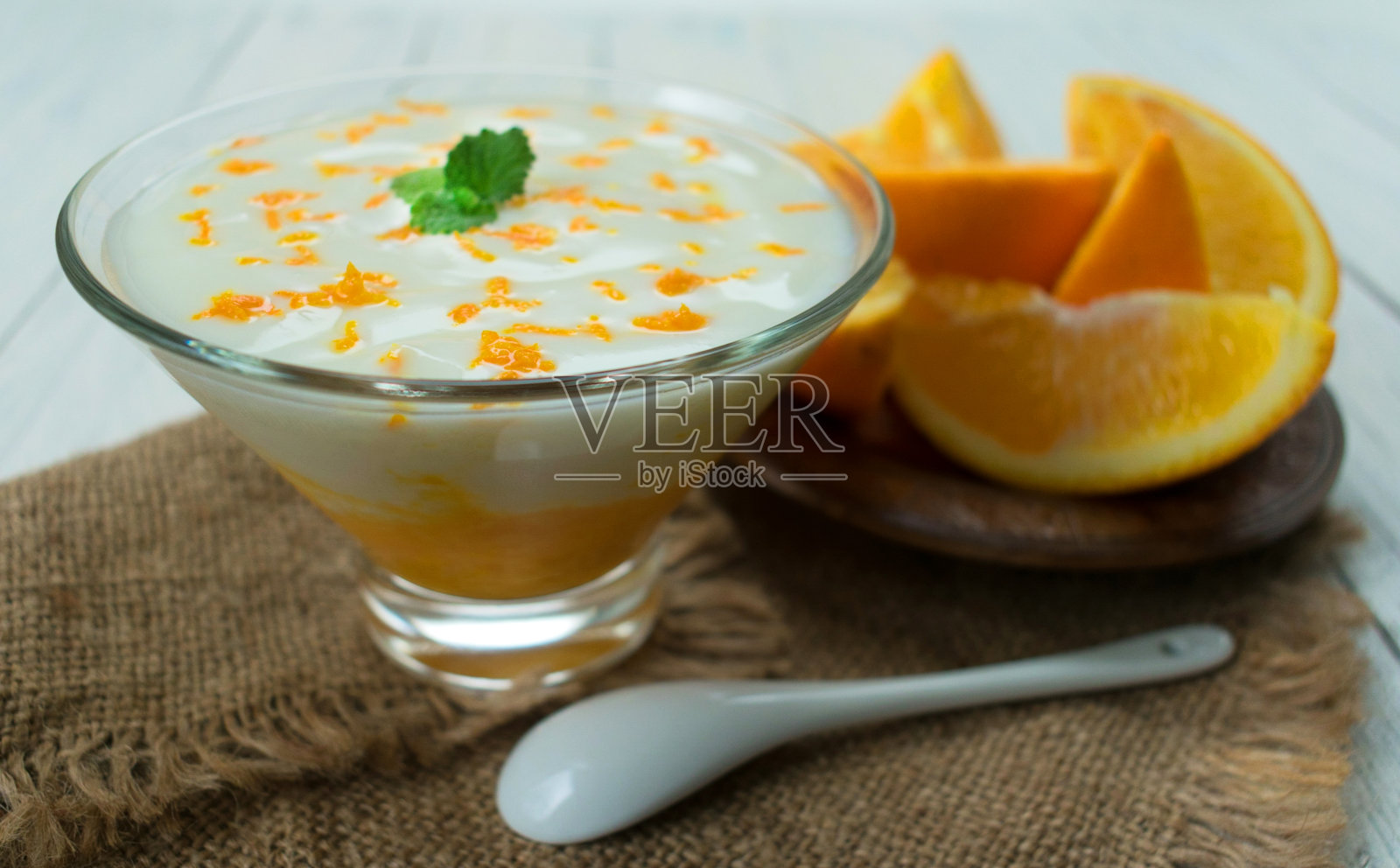 白色的木桌上放着美味的酸奶和橙汁。健康甜点的概念。照片摄影图片