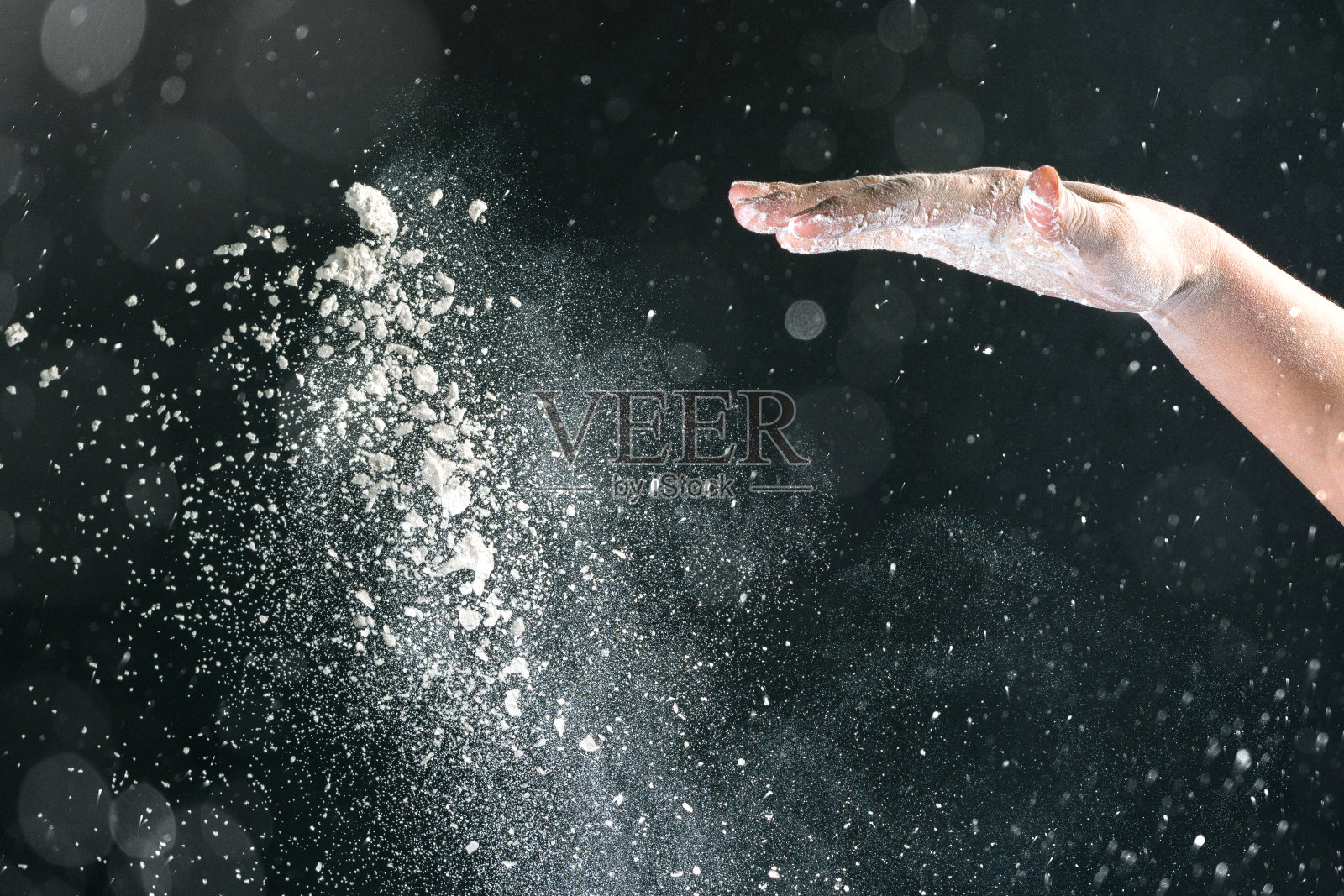 孤立的黑色背景上，女性的手倒着白面粉像雪一样烘烤照片摄影图片