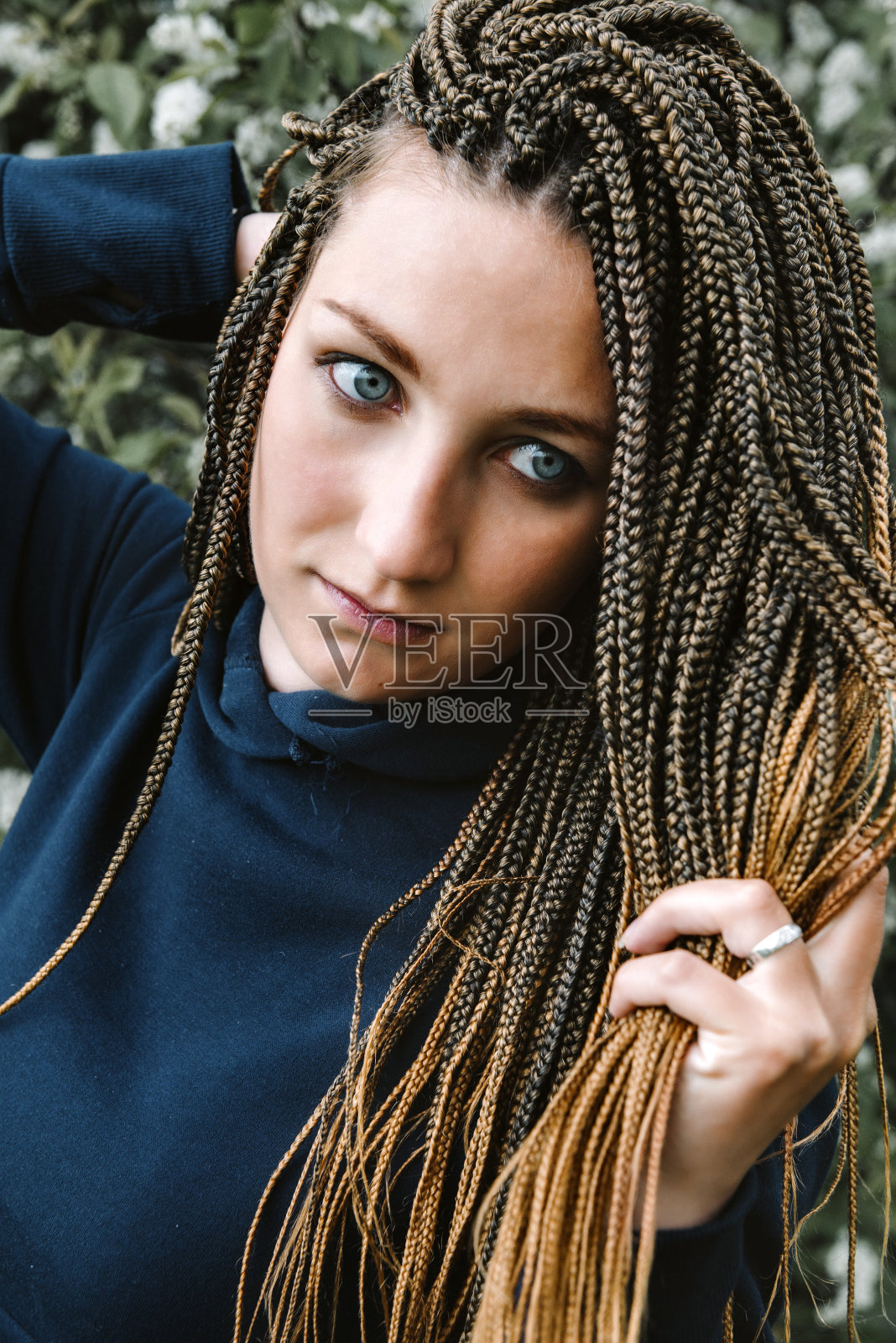 一幅年轻白人妇女的肖像，扎着非洲人的辫子，穿着黑色的连衣裙照片摄影图片