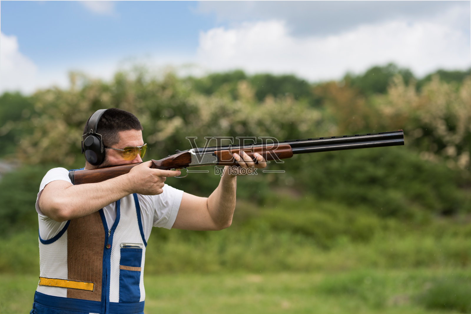 男子用猎枪射击双向飞碟。双向飞碟射击，飞碟飞碟射击。照片摄影图片
