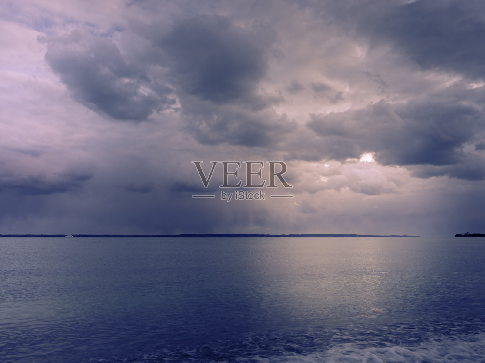 在科德角的干河海滩上，神圣的云和光在海水上反射照片摄影图片