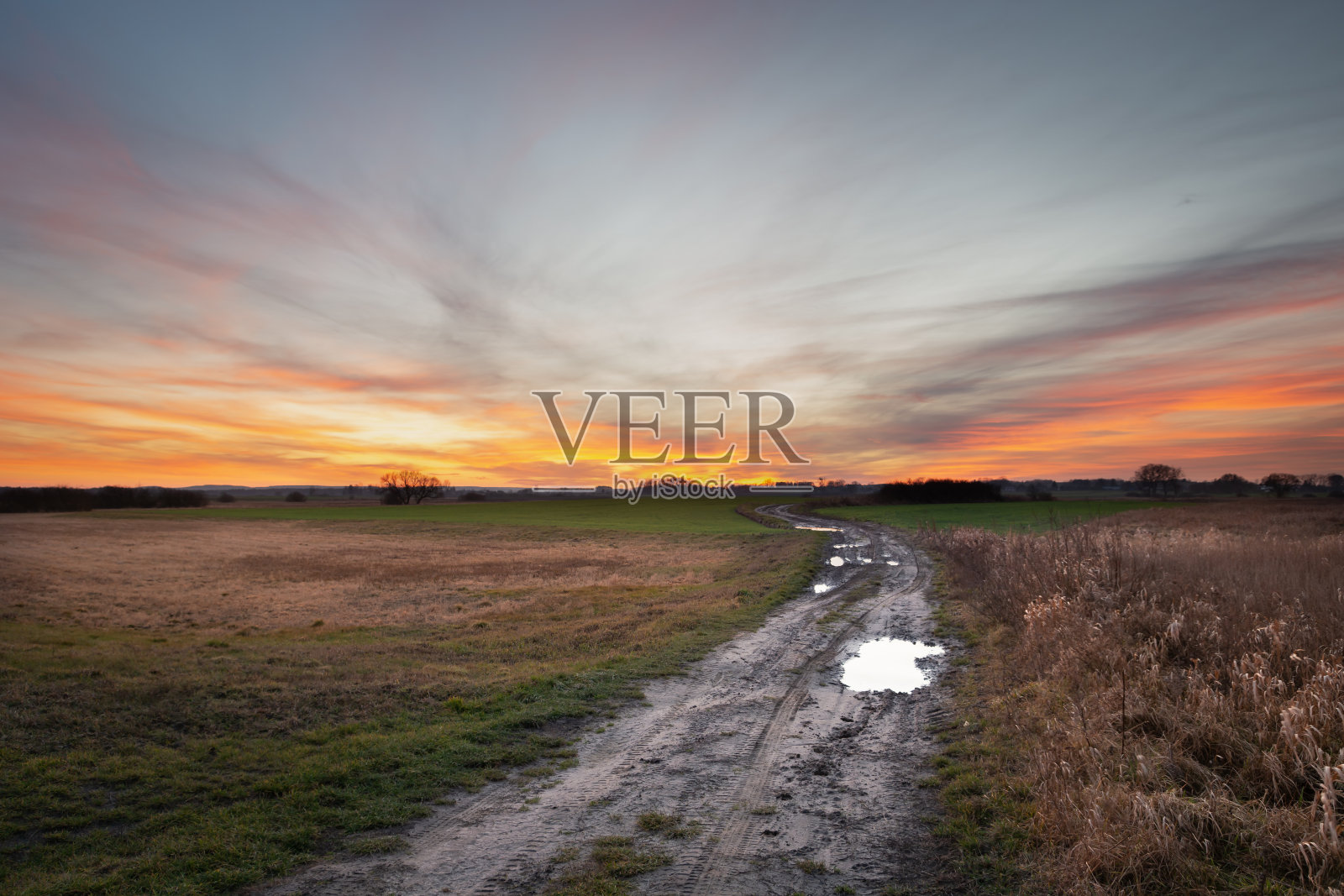 地上的路穿过野生的草地，日落后的地平线和彩云照片摄影图片