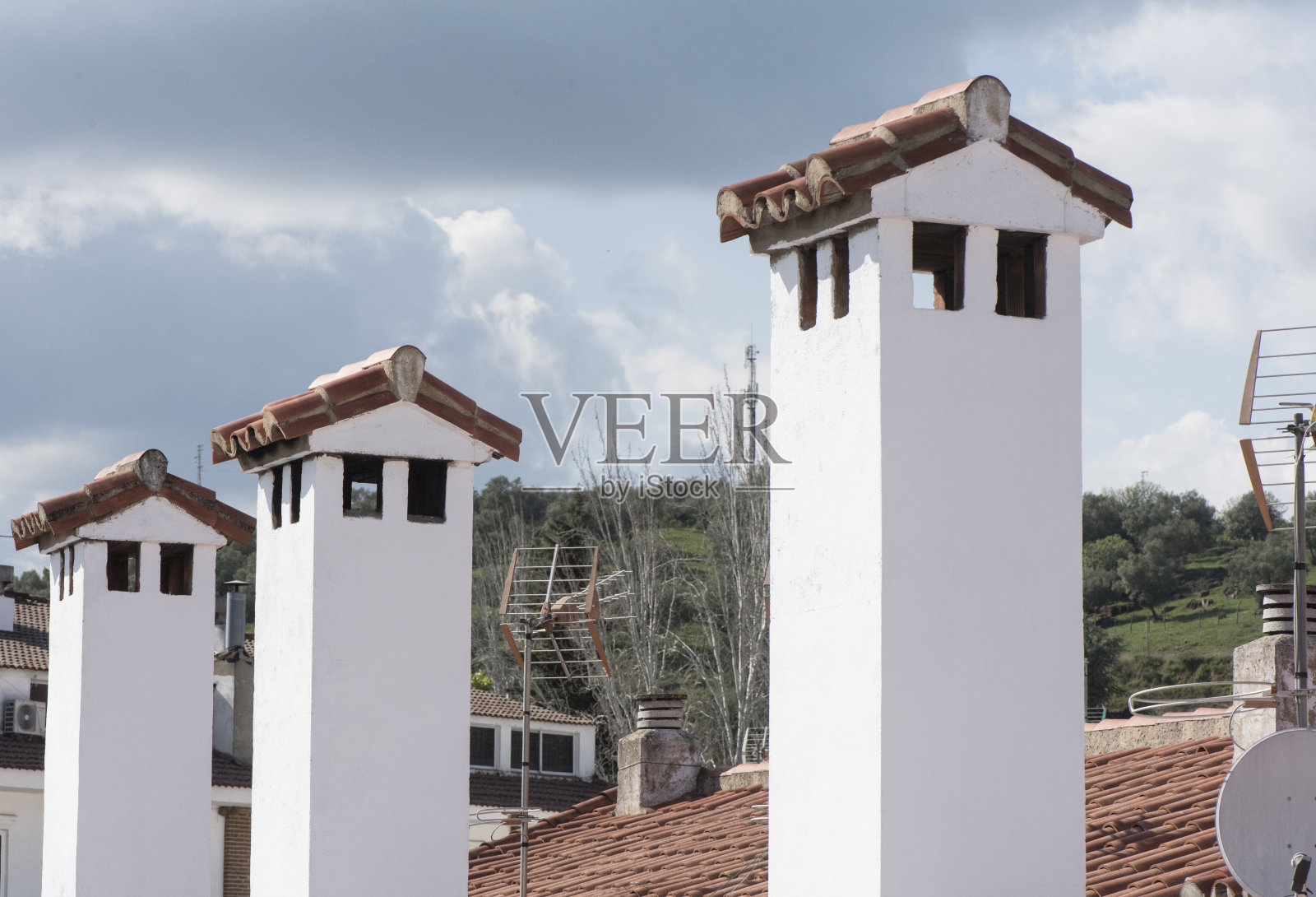 白色的乡村烟囱，石灰电视天线和红色粘土瓦屋顶照片摄影图片