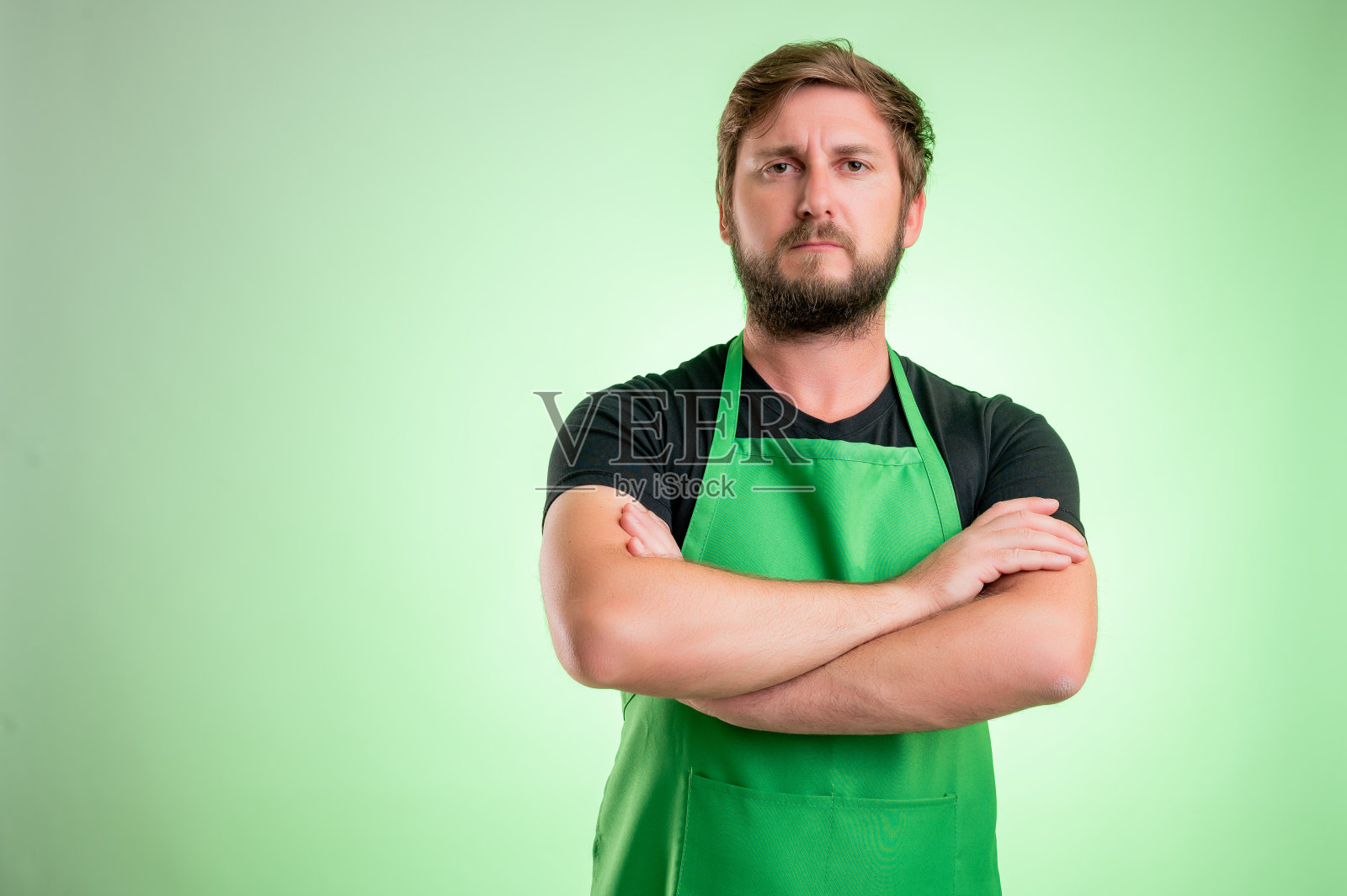 穿着绿色围裙和黑色t恤的超市员工看起来很自信照片摄影图片