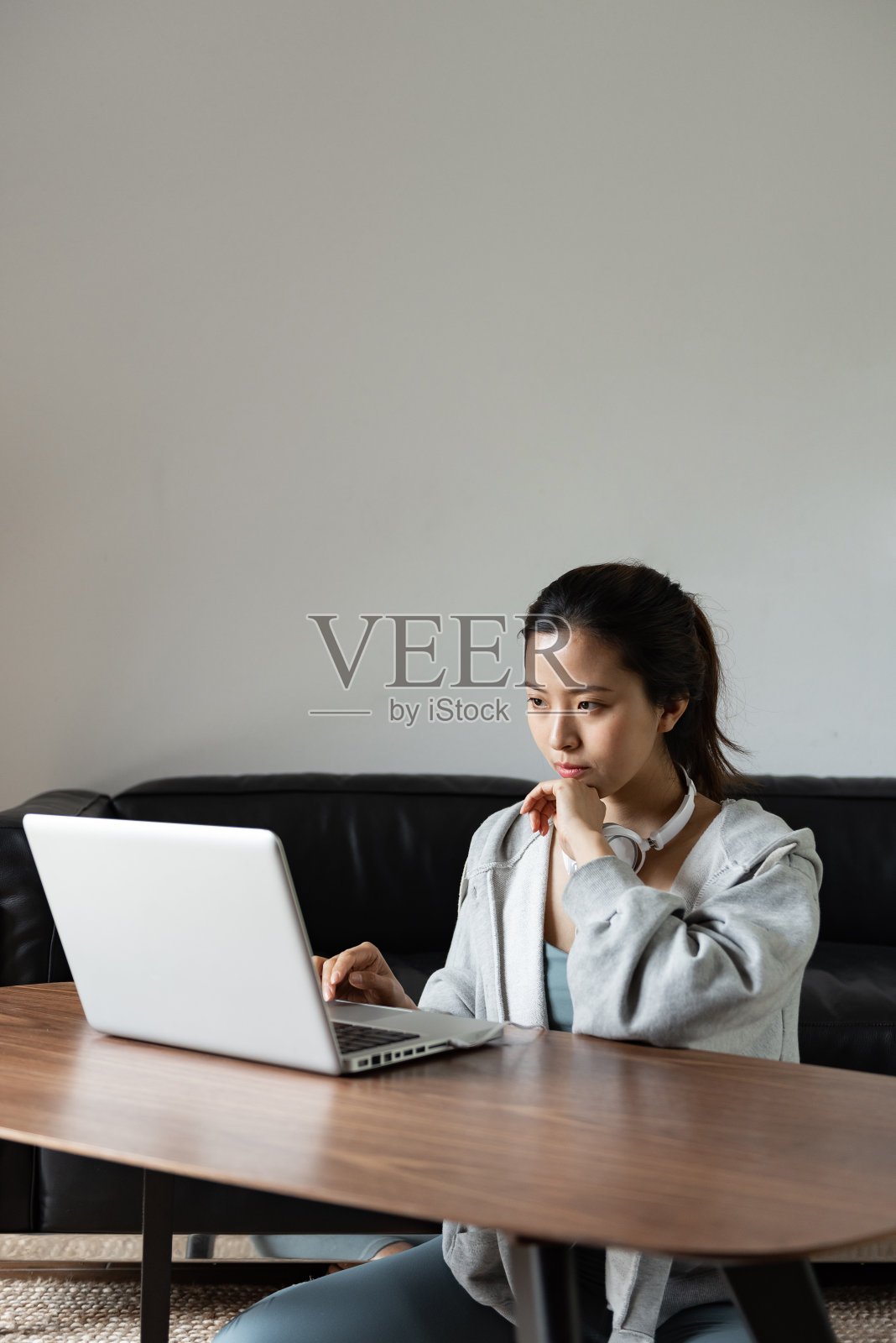 一位年轻的亚洲妇女在客厅里使用电脑照片摄影图片